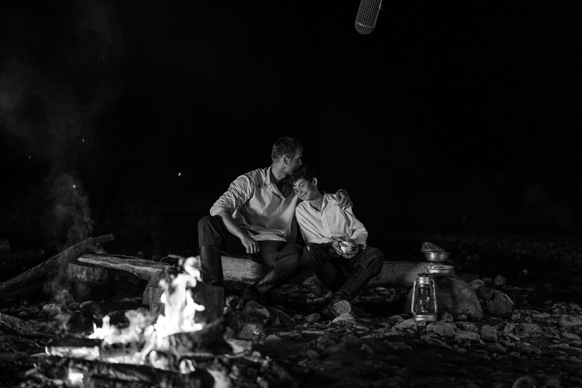 A heartfelt black and white image of a father and son bonding at a night campfire.